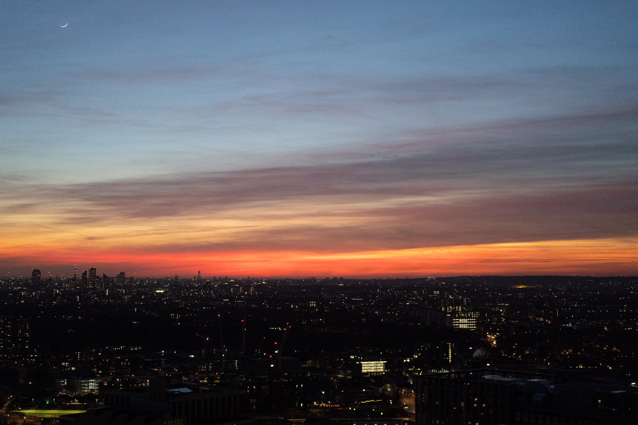 Photo of a sunset with a city skyline where the sky is properly exposed but the buildings appear as dark silhouettes.