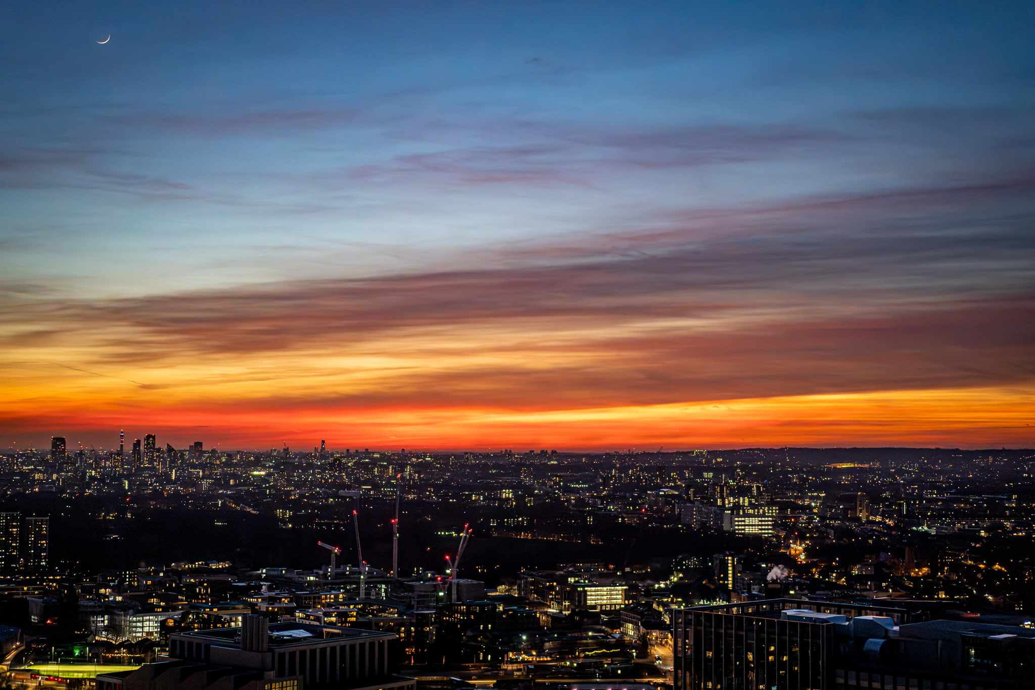 An HDR sunset photo showing both the vibrant orange sky and detailed city skyline buildings.